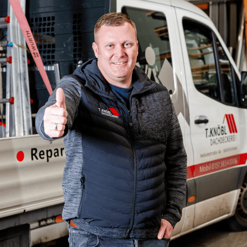 Lächelnder Mann zeigt den Daumen hoch vor einem weißen Transporter der T. Knöbl Dachdeckerei