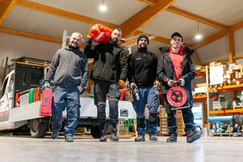 Vier Mitarbeiter mit Werkzeug in der Halle vor einem Transporter